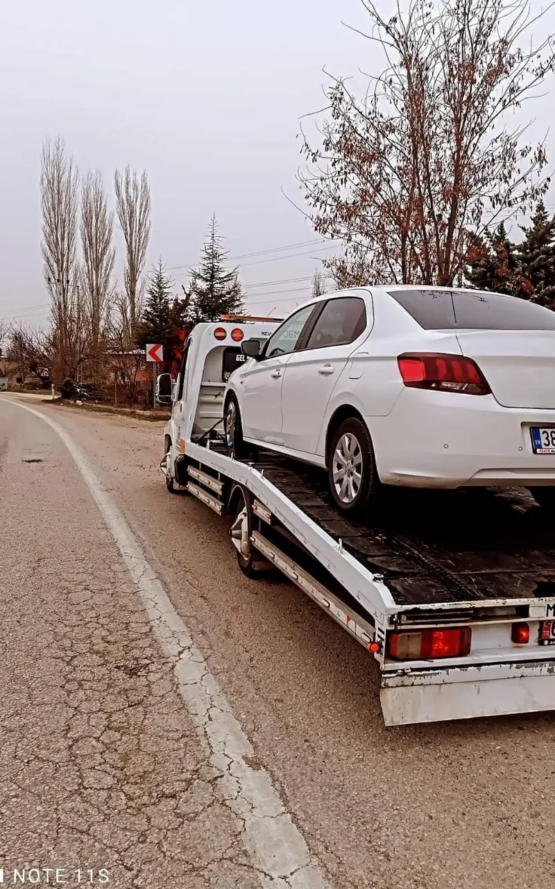 Çekici üzerinde güvenle taşınan beyaz otomobil